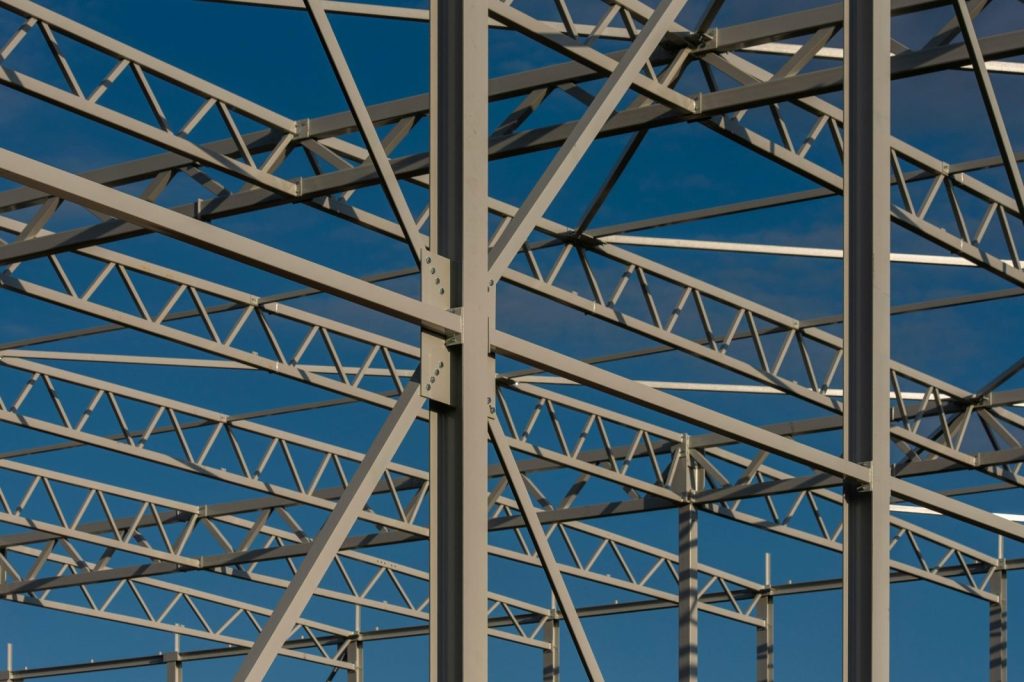 Detailed view of a steel framework structure against a blue sky, showcasing modern construction elements.